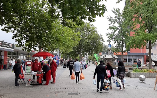 Infostand, Fußgänger mit Einkaufstüten.