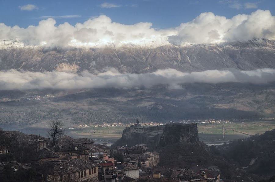 View of gjirokaster castle from above with snow-capped, misty mountains in the background