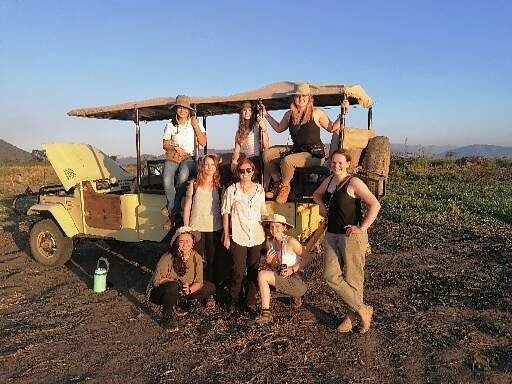 A group of girls pose before a safari truck in Malawi, Africa