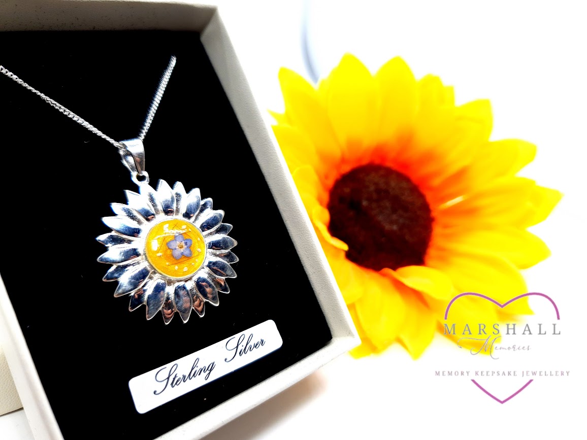 A memory keepsake sterling silver necklace from Marshall Memories with sunflowers in the background as decorations.