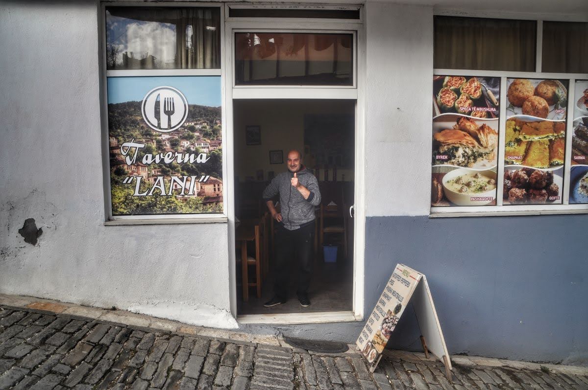 Friendly restaurant owner poses for a picture in front of Taverna Lani in Gjirokaster, Albania