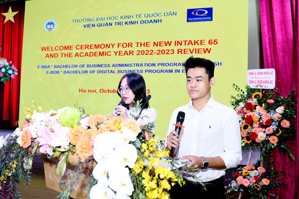 A person and person standing at a podium with microphones

Description automatically generated