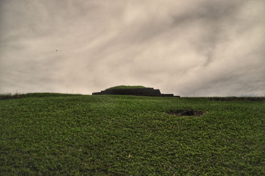 The grassed top of the pyramid protruding above a grassy mound