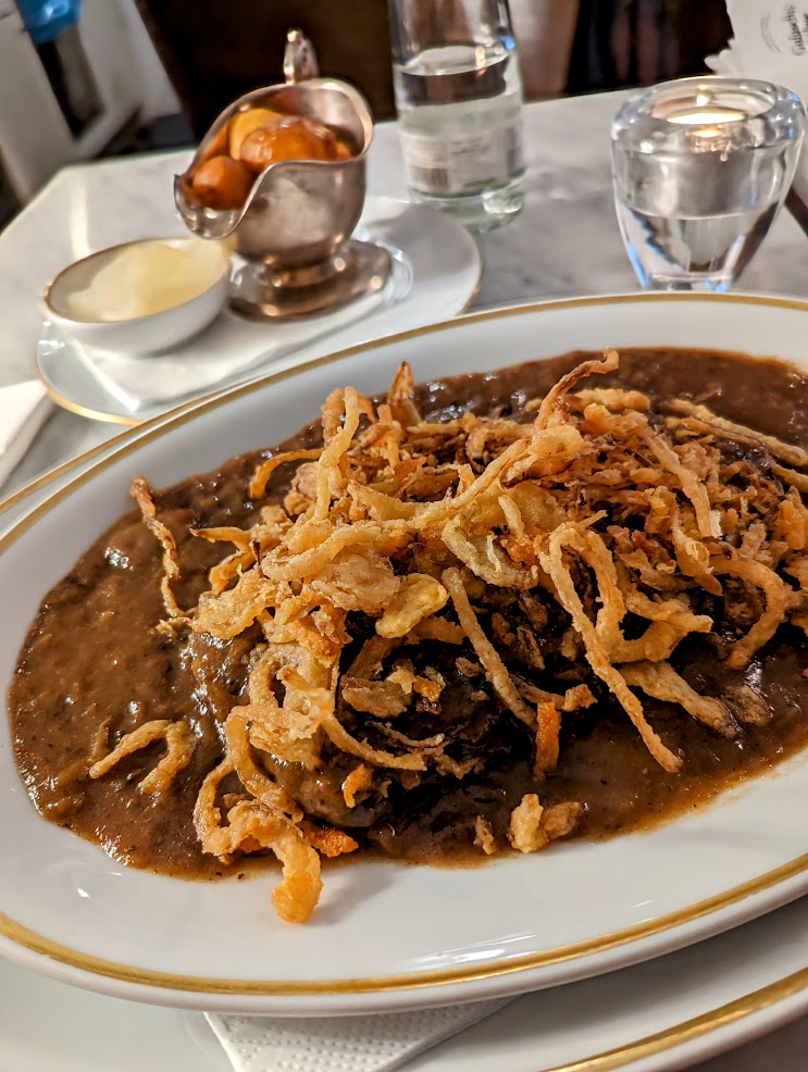 Beef Goulash dish, with lots of gravy. Potatoes in dish with bottle of water too