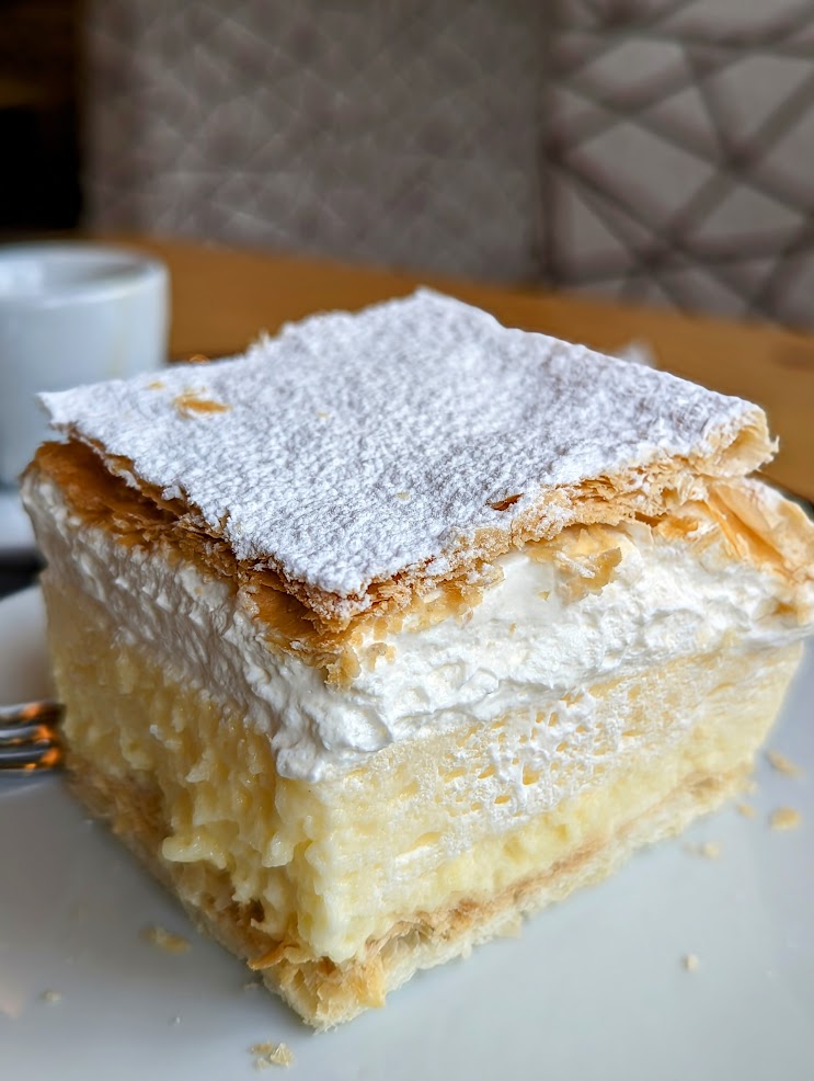 A cake with two thin bits of pastry and cream and custard cut into a square