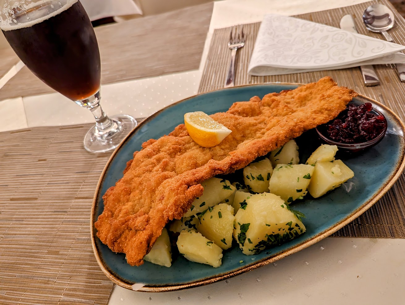 Pork Schnitzel with boiled potatoes and a dark beer on the table