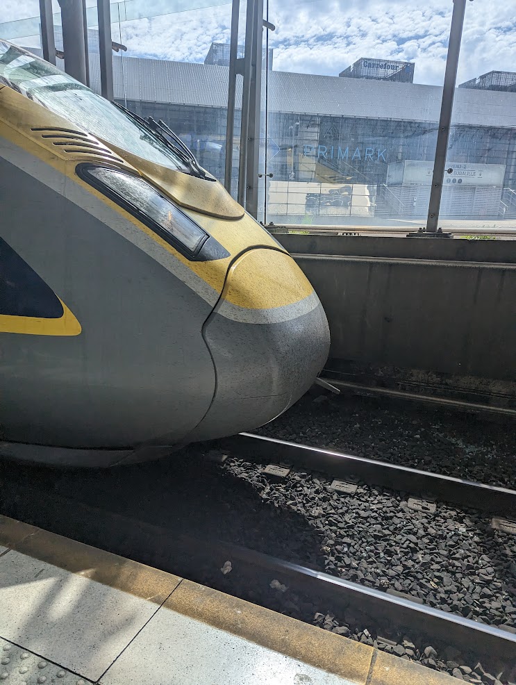 Tip of a Eurostar train pulling with a large Primark can be seen through a window