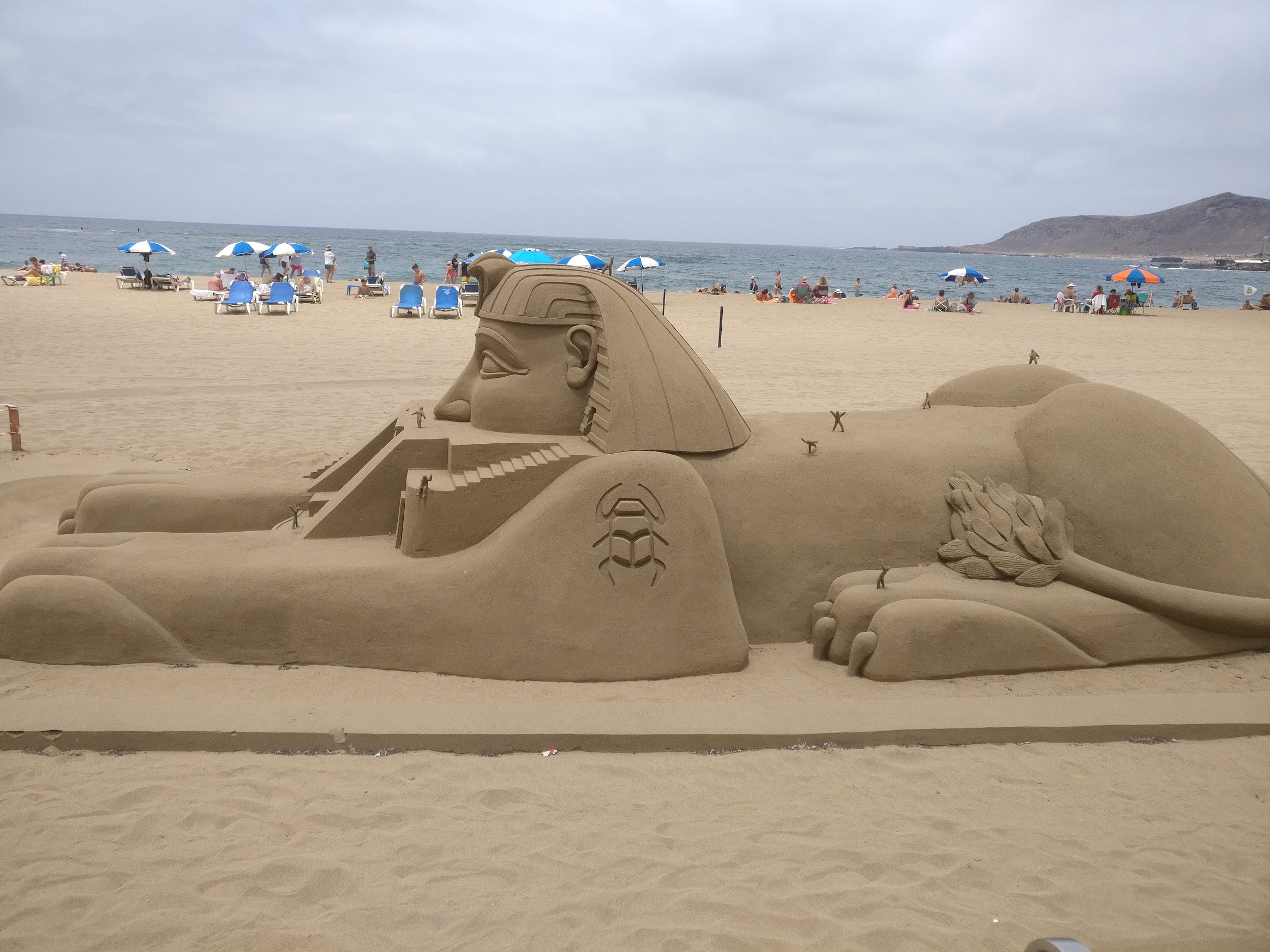 A sphinx statue on the beach, made of sand