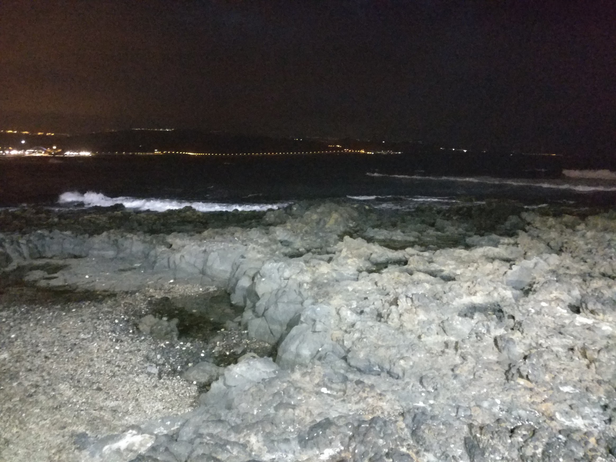 A view of some rocks in the ocean at night