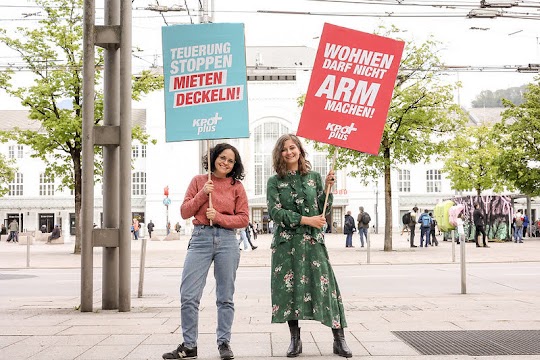 Sarah Pansy und Natalie Hangöbl halten Wahlplakate der KPÖ+ in Salzburg.