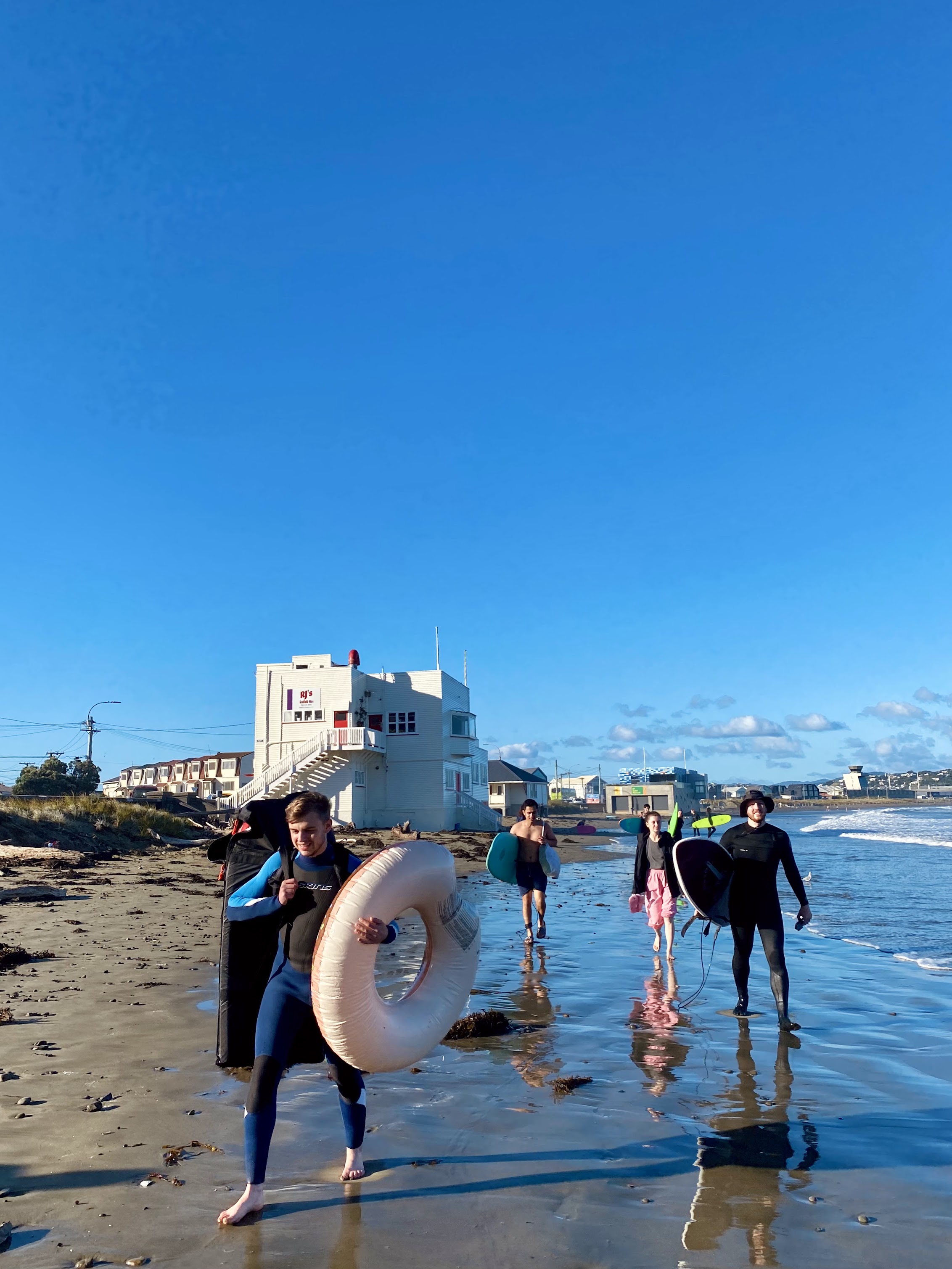 Alex walking down the beach with his boogie board & donut