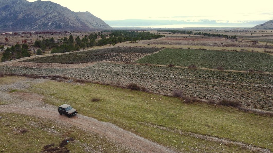 Drone picture of a car with a lake in the distance in Rec, Shkoder County, Albania