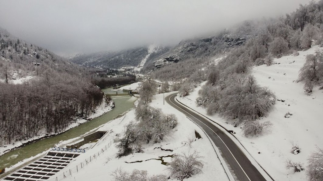 A drone picture of a road passing though snow covered fields and mountains in Valbona Valley, Kukes County, Albania during the winter. 