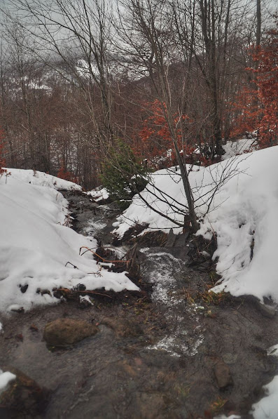 A waterfall running down hill in snowy Vermosh Valley, Shkoder County, Albania in the winter