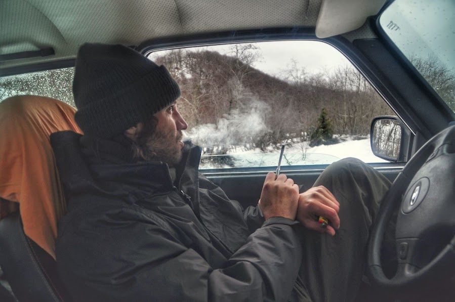 A guy smoking in a 4x4 lada niva car in snowy Vermosh Valley, Shkoder County, Albania in the winter.