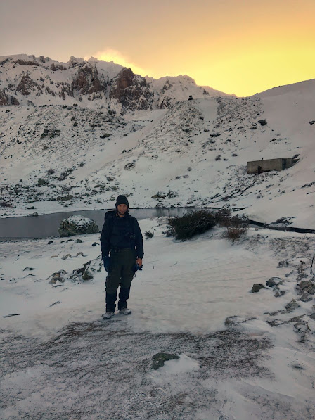 A man standing infront of a tarn on snowy Mount Korab, Diber County, Albania in the winter