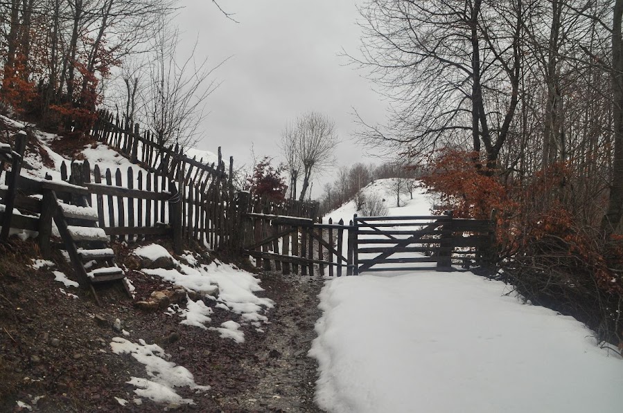 A wooden fence and a stile in the snow in Vermosh Valley, Shkoder County, Albania in the winter.