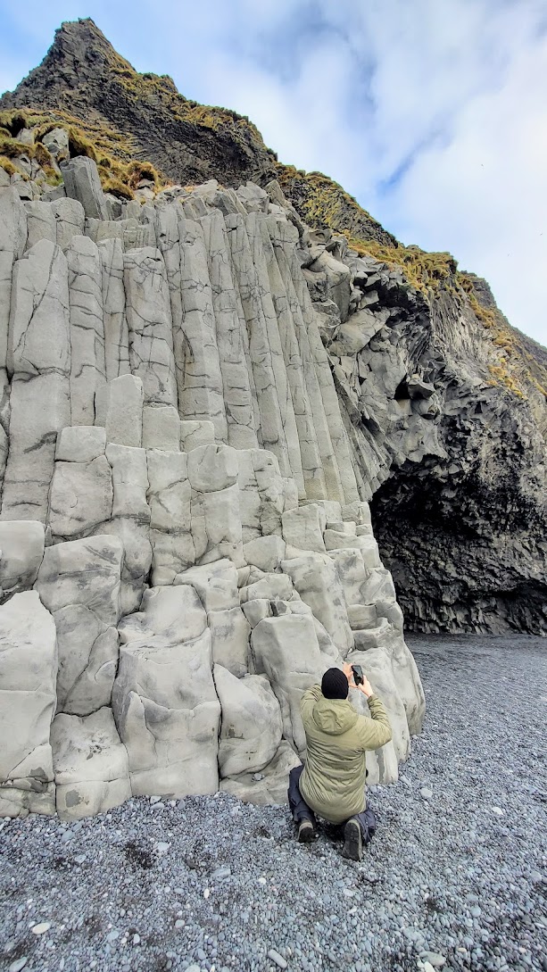 South Iceland Waterfalls and Black Sand Beach: Reynisfjara Black Beach is stunning - you can see the the arched cliff of Dyrhólaey looming over the sea. You can walk on the black sand with pounding Atlantic waves to basalt stacks reminiscent of a pyramid of organ pipes. Out in the roaring sea, you can see sea stacks that may have once been trolls