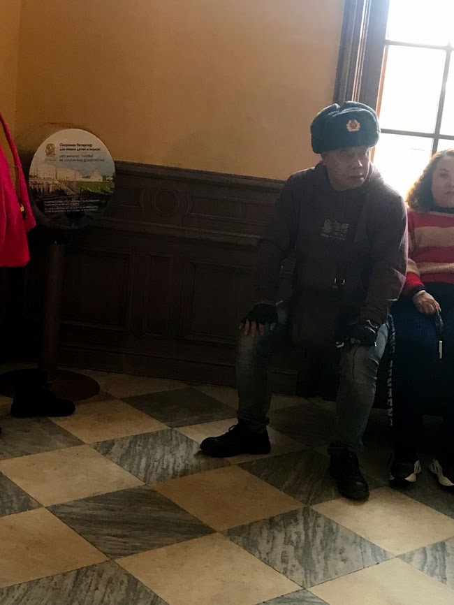 Chinese tourist with Soviet hut at peterhof palace's entrance 