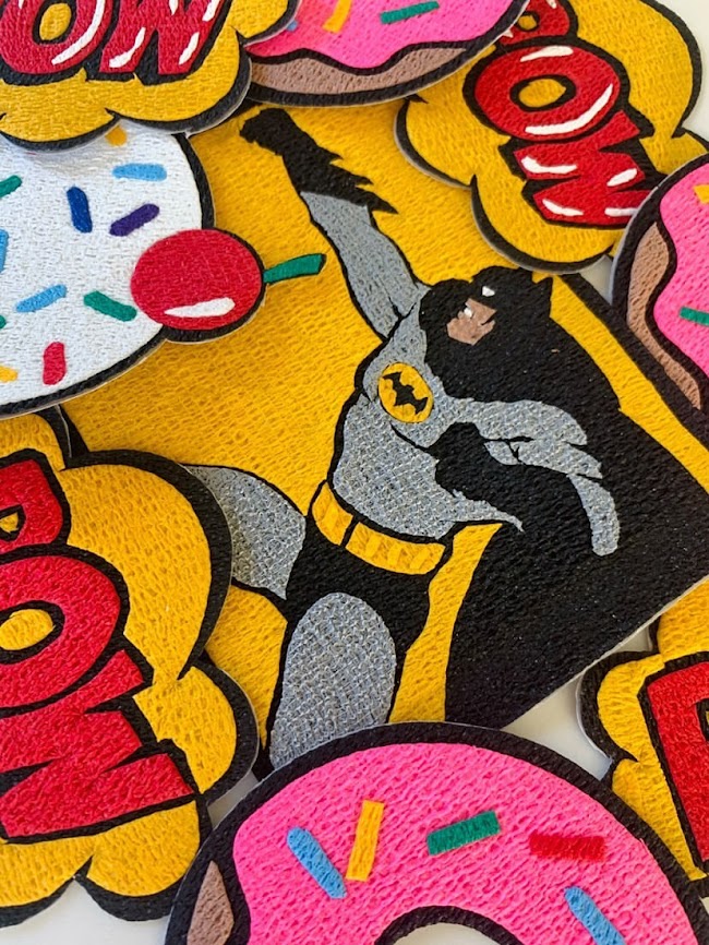 A collection of Bandage Art patches including batman and a pink donut
