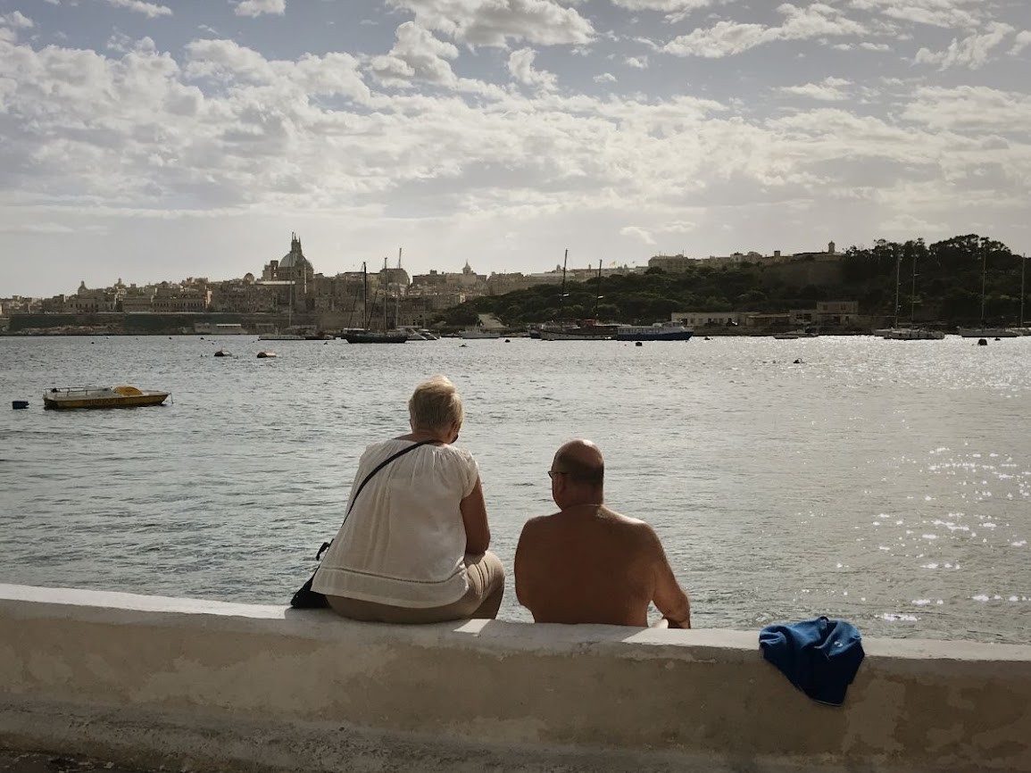 sliema malta couple sitting by the beach and looking at valetta