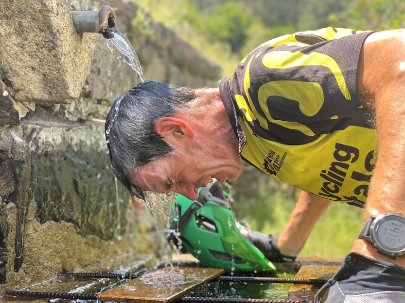 Cyclist lets water run over his head at a fountain