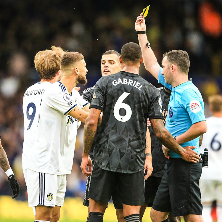 Referee Chris Kavanagh shows a yellow card to Arsenal's Gabriel Magalhaes during their match against Leeds United