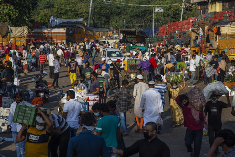 Indians carry sacks of fruits and vegetables in a crowded marketplace as India remains under extended lockdown due to the coronavirus in New Delhi, India.