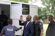 Harry Gwala district mayor Mluleki Ndobe waves before entering a police van to consult his lawyer ahead of his appearance in the Umzimkhulu Magistrate's Court on Monday.