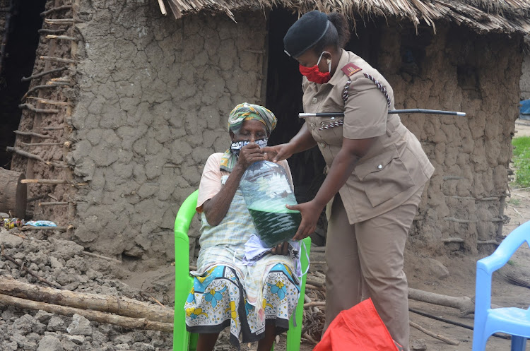 Mbalamweni assistant chief Juliet Mapenzi distributes liquid soap to Sidi Kithuku for washing hands during the Covid-19 pandemic