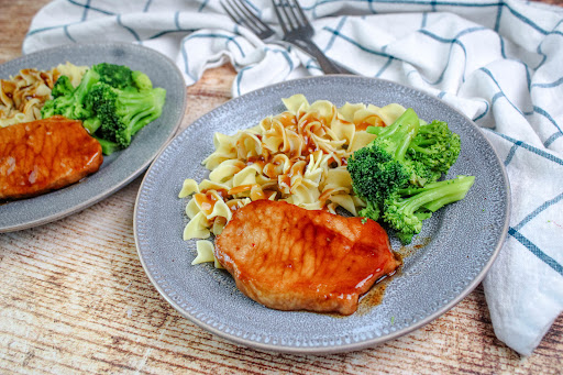 Pork Chops on a platter with noodles and broccoli.