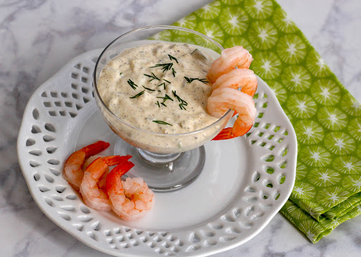 Dill tartar sauce in a serving dish with shrimp.