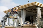 Israeli sappers stand on a crane as they work on a house that the Israeli military said was hit by a rocket fired from the Gaza Strip, in Beersheba, southern Israel October 17, 2018. 