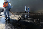 Workers clean up after an above ground oil pipeline ruptured causing some 10,000 gallons of crude oil to spill into the streets of Los Angeles. AFP PHOTO