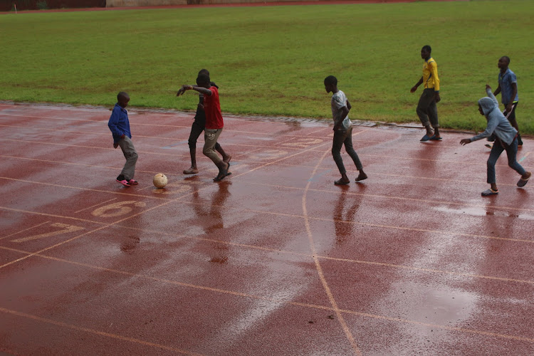 Children play football at the Gusii Stadium running track after heavy rains on Saturday