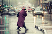 A person crosses Cape Town's Adderley and Darling streets in the rain. A cold front is expected to hit Cape Town early in the Easter weekend and spread inland over the next days, says the weather service. File image