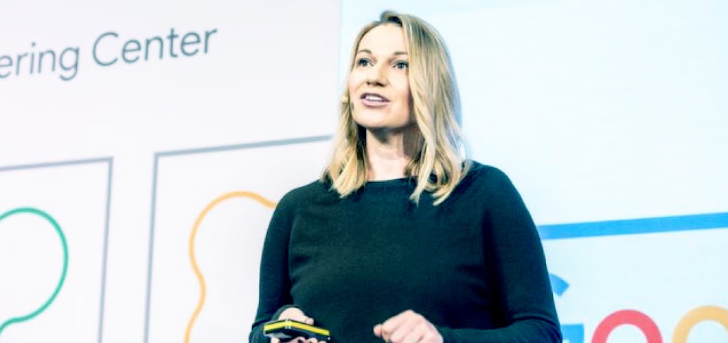 Mulher fala em uma conferência com plano de fundo do Google