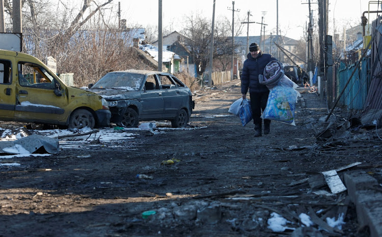 A local resident carries his belongings while walking along a street damaged during Ukraine-Russia conflict in the separatist-controlled town of Volnovakha in the Donetsk region of Ukraine on March 12 2022.