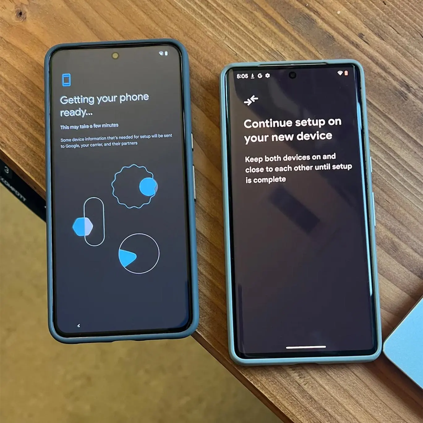 A Pixel 8 Pro sits on a desk next to a Pixel 7 Pro. The Pixel 8 Pro’s screen says “Getting your phone ready” and has details about the process below. The Pixel 7 Pro says “Continue setup on your new device. Keep both devices on and close to each other until setup is complete."