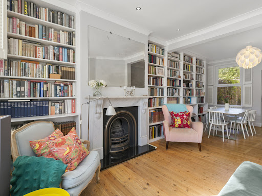 Living room with bookshelves, fireplace, armchair in this luxury house for sale in London ($1,212,146)