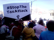 A protester holding a 'Stop The Tax Attack' placard at the Freedom Movement's protest against rising cost of fuel.