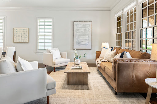 Living room with leather sofa and white armchairs in this luxury house for sale in Cumming ($1,019,000)