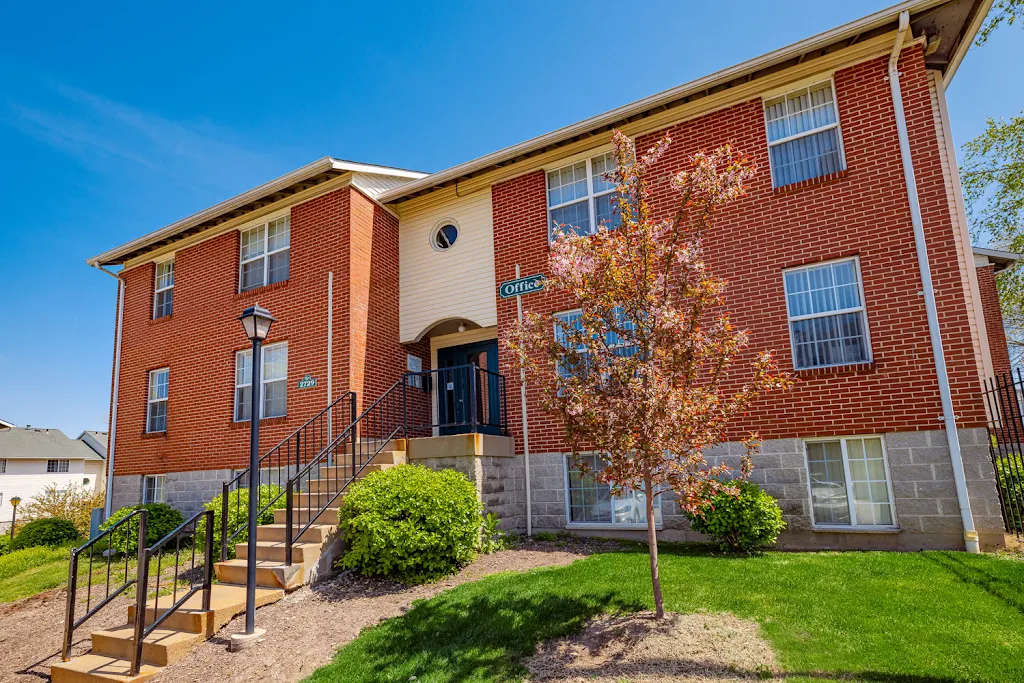 Leasing office building with red brick exterior, steps up to front door, and landscaping