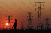 A man walks past electricity pylons during a outage in Orlando, Soweto.