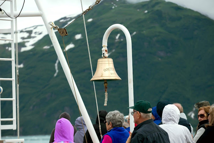 A bell commemorates an early voyage on ms Oosterdam as passengers view the Hubbard Glacier. 