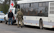 A service member of pro-Russian troops walks next to a bus as civilians from Mariupol, including evacuees from Azovstal steel plant, travel in a convoy to Zaporizhzhia, during Ukraine-Russia conflict in the Donetsk Region, Ukraine on May 2, 2022. 