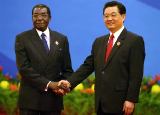 Chinese President Hu Jintao, right, shakes hands with Zimbabwe President Robert Mugabe during the Welcoming ceremony for the Beijing Summit of the Forum on China-Africa Cooperation held at the Great Hall of the People in Beijing, China Saturday, Nov. 4, 2006. China's President Hu Jintao opened a summit with dozens of African leaders Saturday by pledging to double Chinese aid to Africa, provide billions of dollars in loans and build hospitals and schools as it tries to expand ties. Pic. Elizabeth Dalziel. © AP.