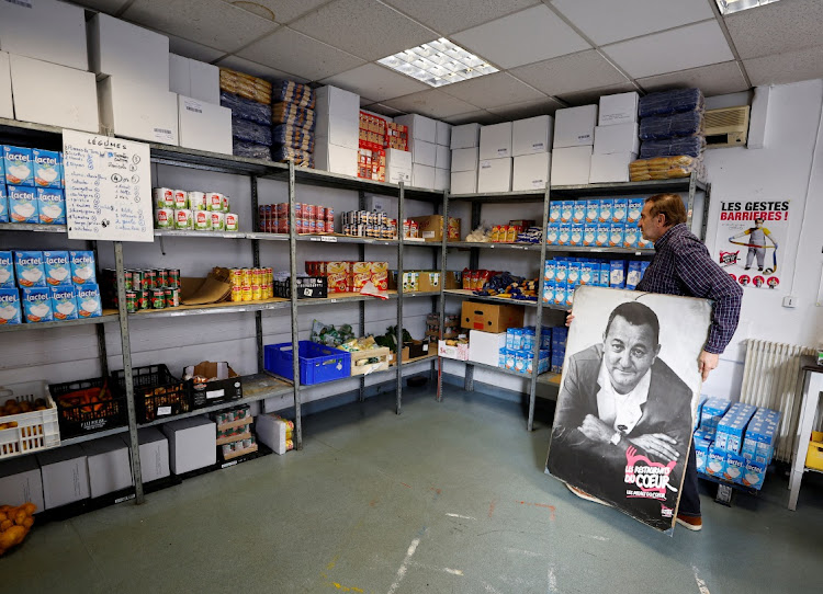 A volunteer holds a poster with a portrait of late French comic Coluche as he walks in a charity food distribution centre "Les Restos Du Coeur" (Restaurants of the Heart) in Nice, France, November 22, 2022. REUTERS/ERIC GAILLARD/FILE PHOTO