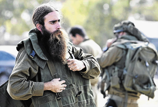 WAR ZONE: An Israeli army reservist adjusts his gear in a staging area outside the Gaza Strip on Friday. Israel stepped up its land offensive in Gaza with artillery, tanks and gunboats on Friday and declared it could 'significantly widen' an operation Palestinian officials said was killing ever greater numbers of civilians