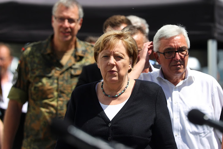 Rhineland-Palatinate’s interior minister, Roger Lewentz, stands behind German Chancellor Angela Merkel as she speaks during a news conference in the flood-ravaged village of Schuld, near Bad Neuenahr-Ahrweiler, Rhineland-Palatinate state, Germany, on July 18. Picture: Reuters/Wolfgang Rattay